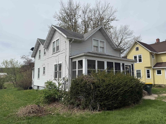 rear view of property featuring a yard and a sunroom