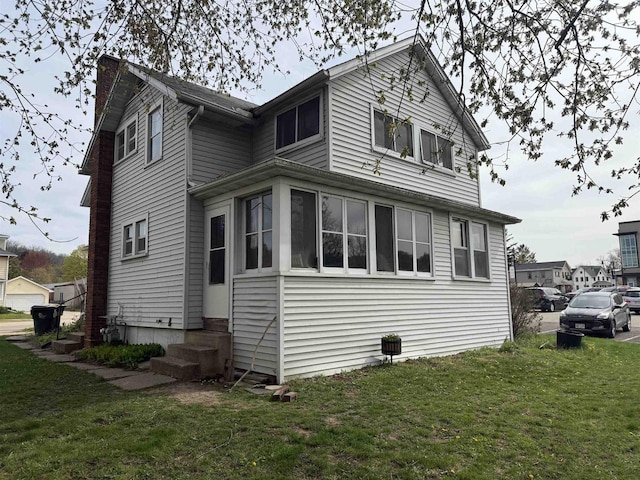 view of side of property featuring a yard, a chimney, and entry steps