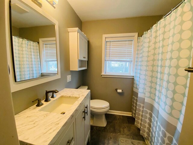 full bath with vanity, stone finish flooring, curtained shower, and toilet