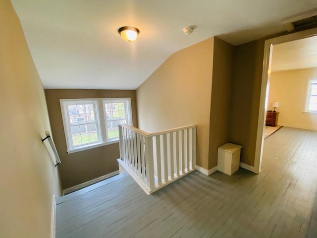 additional living space with baseboards, wood-type flooring, vaulted ceiling, and visible vents