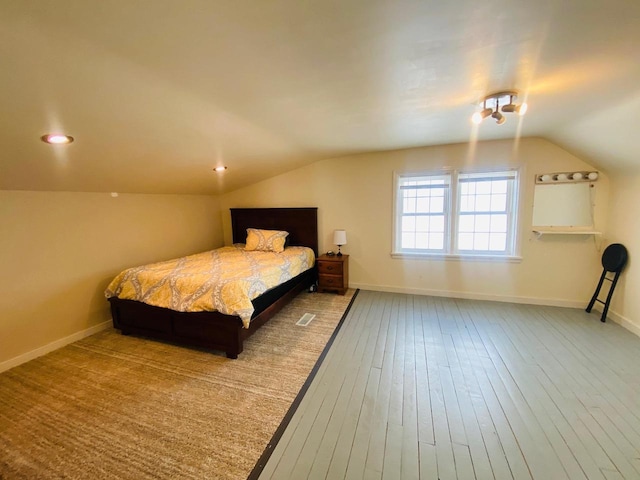 bedroom featuring baseboards, wood-type flooring, and lofted ceiling