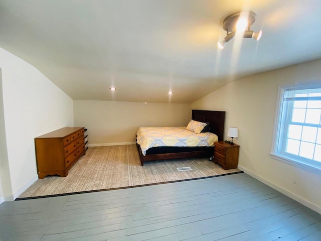bedroom featuring baseboards, vaulted ceiling, and light wood-style flooring