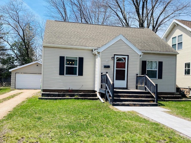 bungalow featuring a shingled roof, an outbuilding, a front yard, and a detached garage