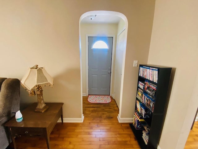 entryway with baseboards, arched walkways, and hardwood / wood-style flooring