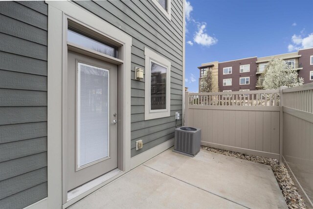 entrance to property featuring a patio, fence, and cooling unit
