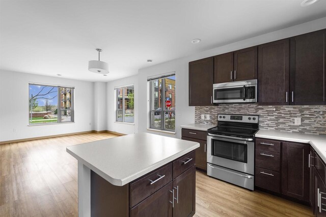 kitchen with open floor plan, light countertops, tasteful backsplash, light wood finished floors, and stainless steel appliances