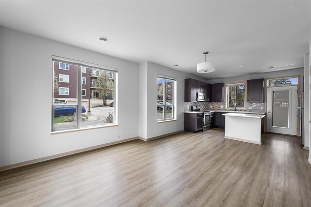kitchen with tasteful backsplash, wood finished floors, light countertops, a sink, and stainless steel appliances