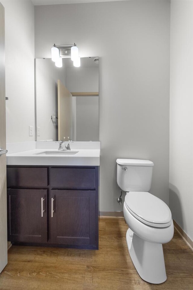 bathroom with vanity, baseboards, wood finished floors, and toilet