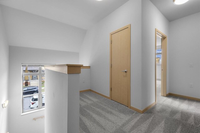 corridor with baseboards and carpet flooring