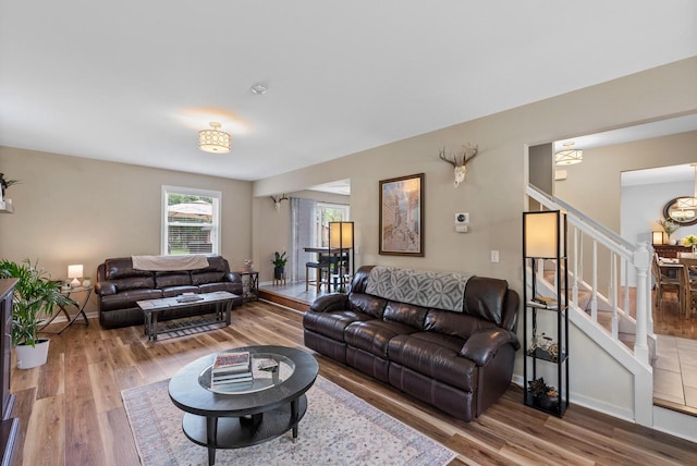 living area featuring stairs, an inviting chandelier, and wood finished floors