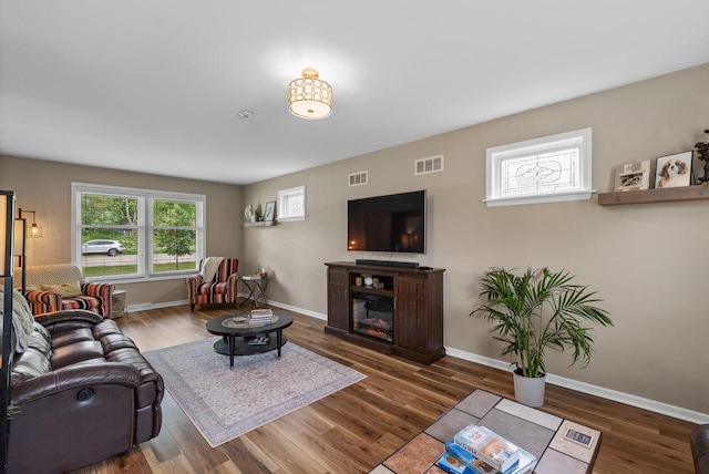 living room featuring baseboards, wood finished floors, and visible vents