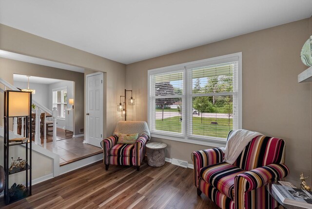 sitting room with baseboards, visible vents, wood finished floors, and stairway