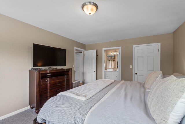 bedroom with baseboards, carpet flooring, and ensuite bath