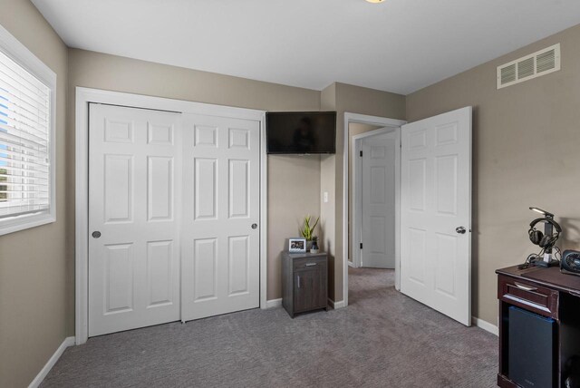 carpeted bedroom featuring visible vents, baseboards, and a closet