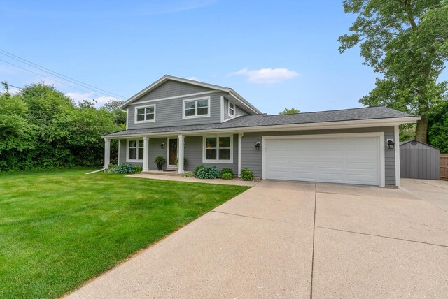 traditional-style home with roof with shingles, a garage, a front yard, covered porch, and driveway