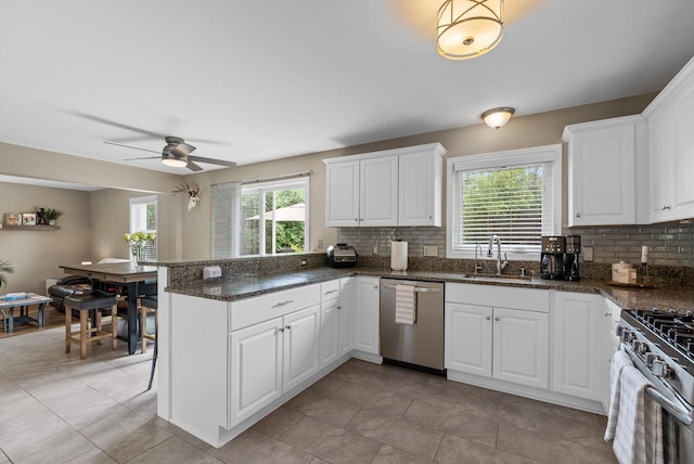 kitchen featuring decorative backsplash, a ceiling fan, appliances with stainless steel finishes, a sink, and a peninsula