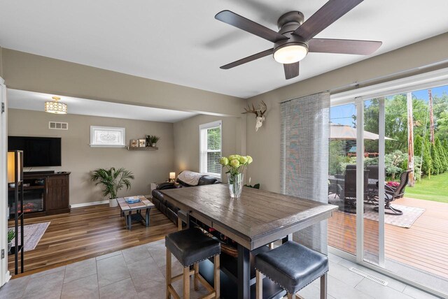 dining space with light tile patterned flooring, ceiling fan, visible vents, and baseboards