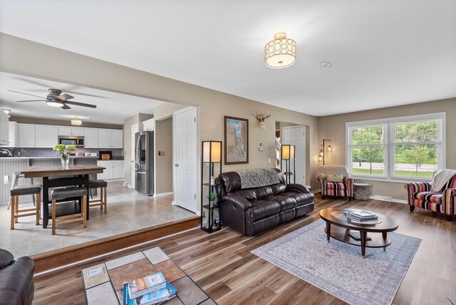 living area featuring baseboards, ceiling fan, and light wood-style flooring
