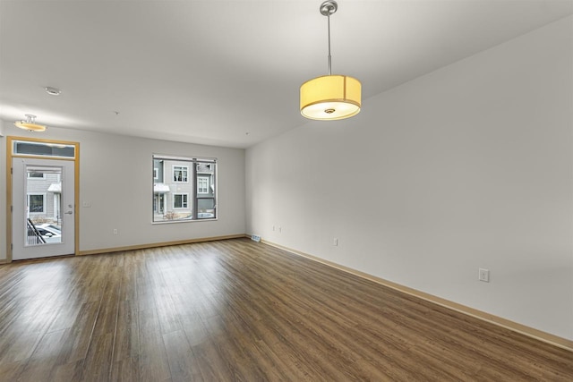 unfurnished room with baseboards, wood finished floors, and a healthy amount of sunlight