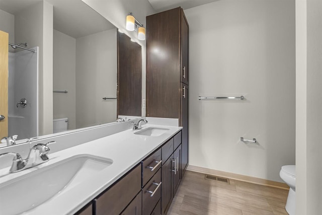 full bath with toilet, baseboards, visible vents, and a sink