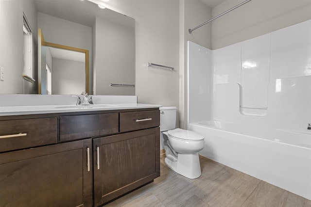 bathroom with toilet, shower / bath combination, wood finished floors, and vanity