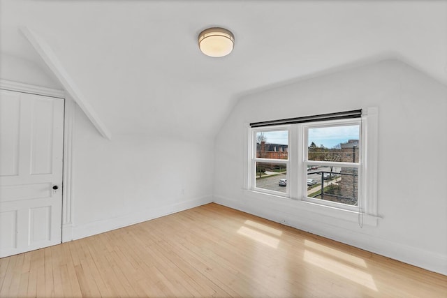 additional living space with baseboards, hardwood / wood-style flooring, and lofted ceiling
