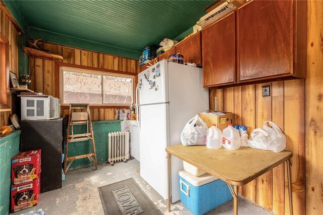 W12141 Hwy 8, Bruce, WI 54819 - kitchen with radiator, freestanding refrigerator, concrete flooring, and wood walls