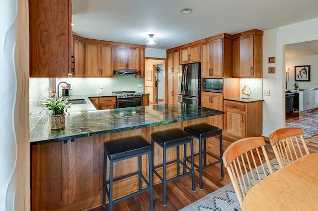 6610 Whittlesey Rd, Middleton, WI 53562 - kitchen featuring stainless steel appliances, a sink, under cabinet range hood, wood finished floors, and decorative backsplash