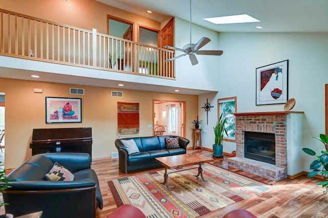 6610 Whittlesey Rd, Middleton, WI 53562 - living room featuring wood finished floors, a skylight, a fireplace, ceiling fan, and a towering ceiling