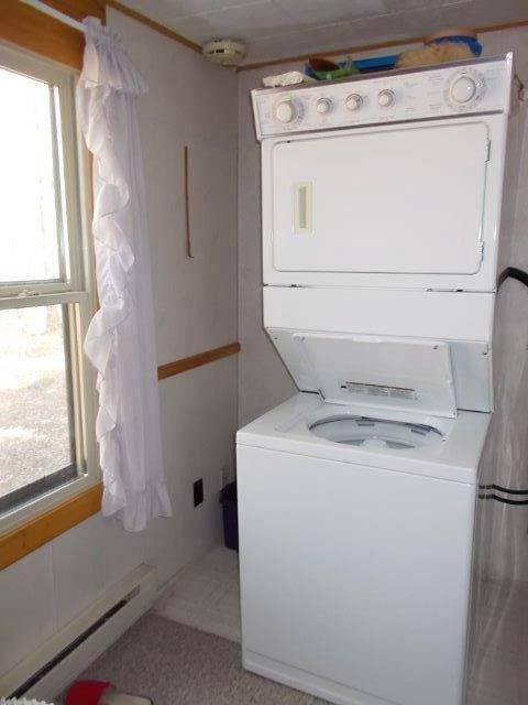 laundry area with stacked washer and clothes dryer and a baseboard radiator