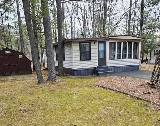 manufactured / mobile home with a storage unit, a front lawn, an outbuilding, and entry steps