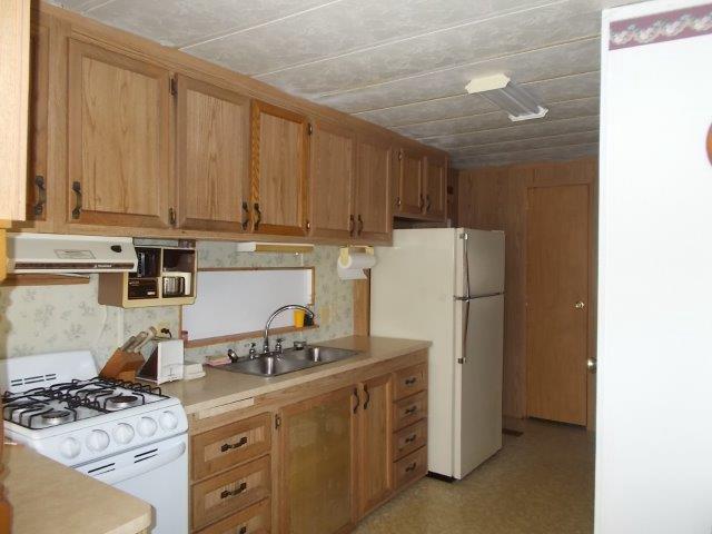kitchen featuring brown cabinetry, white appliances, extractor fan, light countertops, and a sink