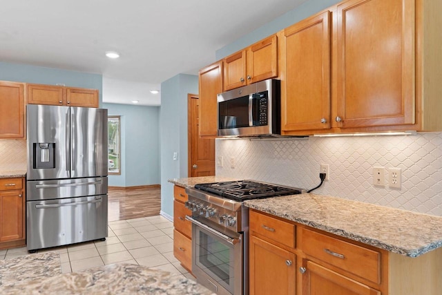 7605 W Windrush Ln, Franklin, WI 53132 - kitchen with appliances with stainless steel finishes, light tile patterned floors, backsplash, light stone countertops, and baseboards