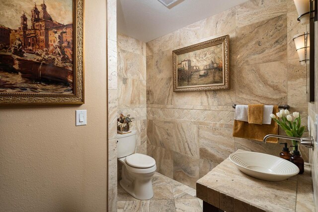 bathroom with vanity, toilet, and tile walls