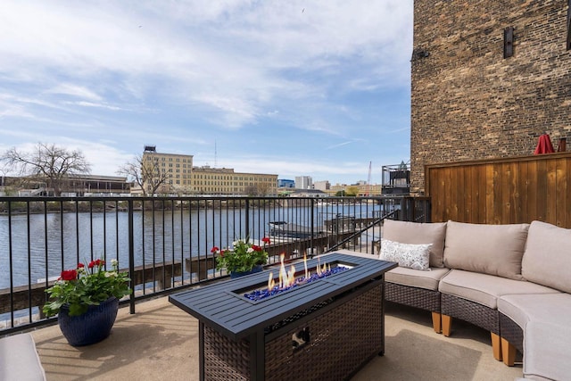 balcony with an outdoor living space with a fire pit and a water view