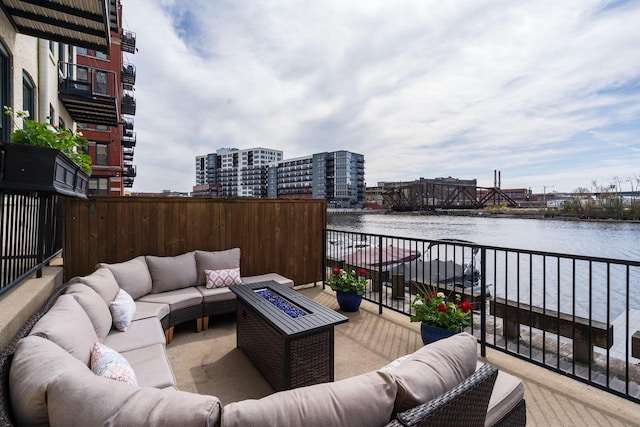 wooden deck with an outdoor living space with a fire pit and a water view