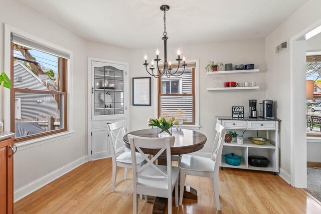 dining space featuring an inviting chandelier, light wood-style flooring, baseboards, and visible vents