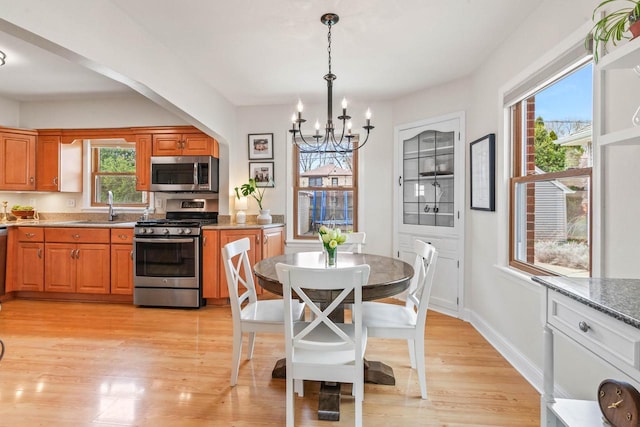 kitchen featuring a sink, appliances with stainless steel finishes, brown cabinetry, and a chandelier