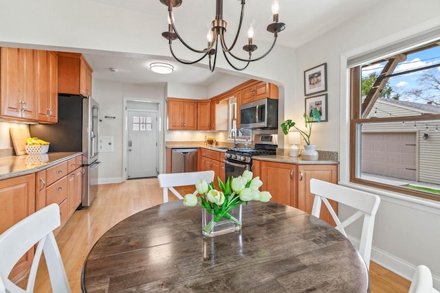 kitchen featuring an inviting chandelier, baseboards, a healthy amount of sunlight, and stainless steel appliances