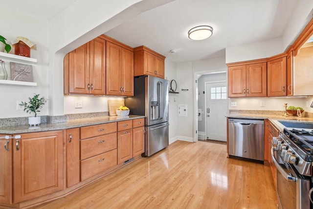 kitchen with brown cabinetry, open shelves, a sink, light wood-style floors, and stainless steel appliances