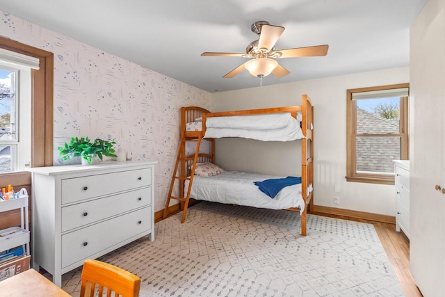bedroom featuring baseboards, ceiling fan, wallpapered walls, and light wood-type flooring