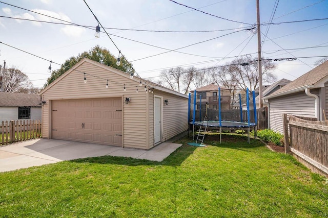 detached garage featuring fence and a trampoline