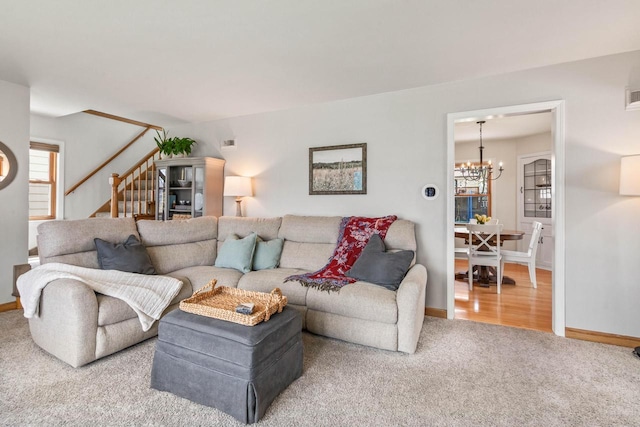 carpeted living area featuring baseboards, a notable chandelier, stairway, and visible vents