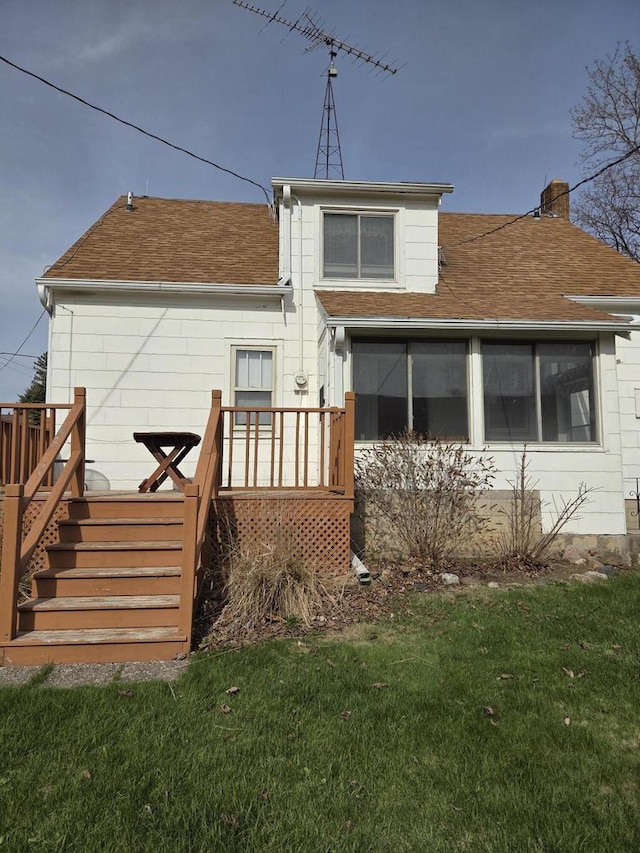 rear view of house featuring a chimney, a lawn, a deck, stairway, and a shingled roof
