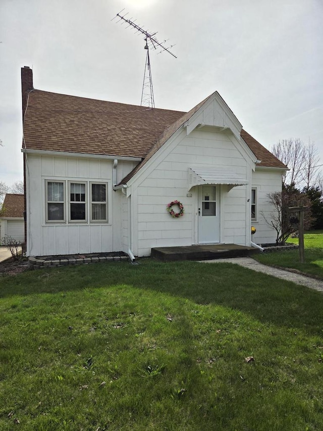 view of front of house with board and batten siding, a chimney, a shingled roof, and a front lawn