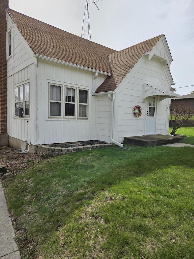 view of front of house featuring roof with shingles, board and batten siding, and a front yard