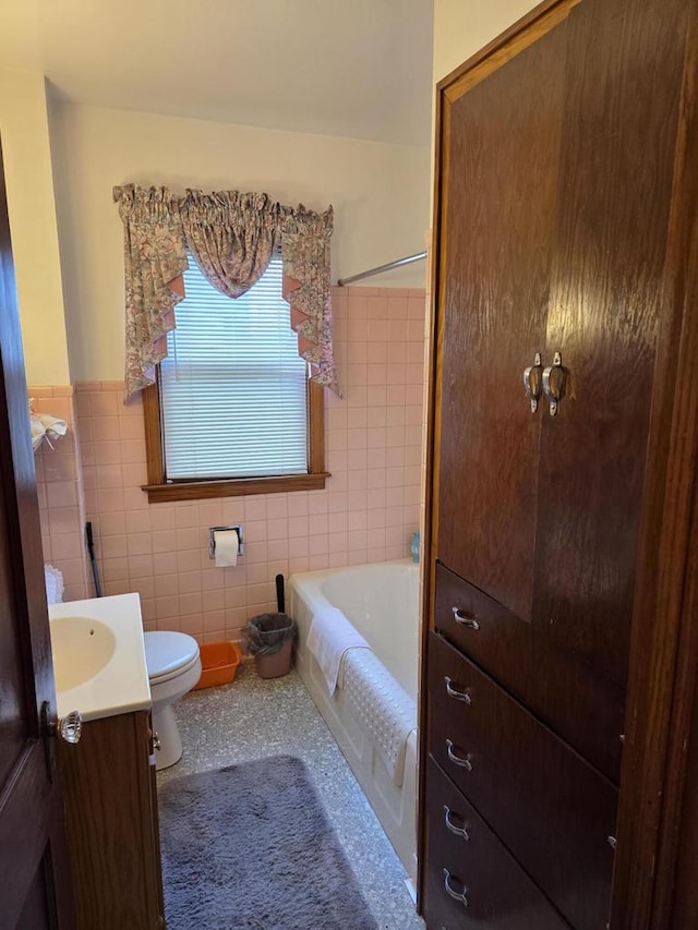 full bathroom featuring wainscoting, vanity, toilet, a bathtub, and tile walls
