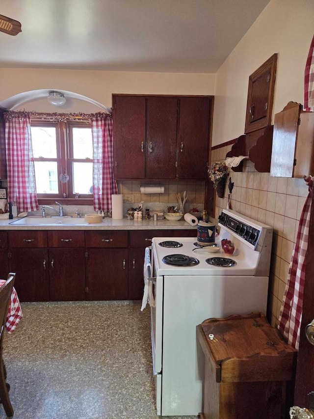 kitchen featuring tile walls, wainscoting, a sink, light countertops, and white range with electric stovetop