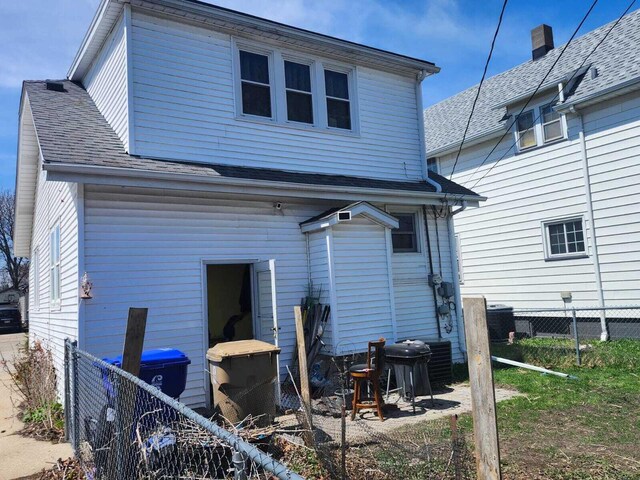 7607 15th Ave, Kenosha, WI 53143 - rear view of house featuring central air condition unit, fence, and roof with shingles