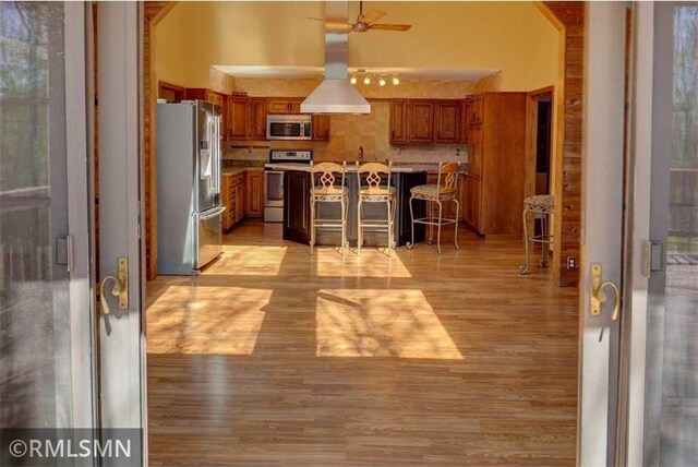890 Lincoln Ave, Amery, WI 54001 - kitchen with brown cabinets, light wood finished floors, stainless steel appliances, a ceiling fan, and a kitchen bar